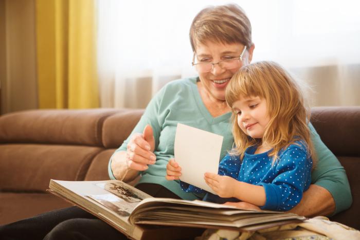 Una abuela junto a su nieta revisan un álbum de fotos
