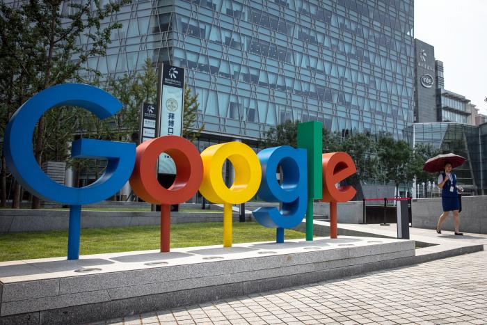 Fotografía de archivo fechada el 3 de agosto de 2018 que muestra a una mujer que camina junto al logo de Google, en las oficinas de dicha firma en Pekín (China).