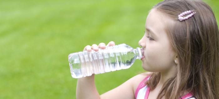 Niña se hidrata bebiendo agua