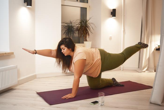 sid-view-of-overweight-obese-young-woman-wearing-t-shirt-and-leggings-doing-physical-training-on-mat-to-strengthen-legs-arms-abs-and-spine-weght-loss-fitness-sports-and-active-lifestyle-concept