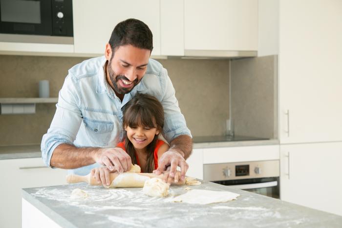 joyful-happy-dad-and-his-girl-enjoying-time-together-while-rolling-and-kneading-dough-in-kitchen