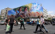 Iraníes pasan frente a una gran valla publicitaria con los difuntos líderes supremos iraníes, los ayatolás Ruhollah Jomeini y Ali Jameneí, en una calle de Teherán, Irán.