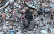 Un hombre se sienta sobre los escombros mientras espera noticias de su familia en el sitio de los edificios derrumbados después de un fuerte terremoto, en Hatay, Turquía, el 15 de febrero de 2023.