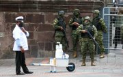 Militares y un vendedor  esperan a las afueras del Palacio de Gobierno en Quito.