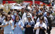 Personas usan sus teléfonos afuera de un edificio luego de ser evacuadas debido a un sismo de 6.1, en Bogotá (Colombia).
