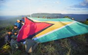 hombres desplegando una bandera de Guyana en la montaña Pakrampa, en la aldea de Arau, región Esequibo (Guyana).