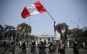 Fotografía de un hombre al ondear una bandera peruana, frente a la sede del Congreso Nacional de Perú, en Lima (Perú).