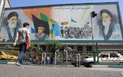 Iraníes caminan junto a una pintura mural del líder supremo iraní, el ayatolá Ali Jameneí (arriba-i) y el fallecido líder supremo iraní, el ayatolá Ruhollah Jomeiní (arriba-d), en una calle de Teherán.