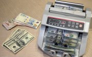 Una ilustración muestra una máquina contando billetes de pesos argentinos junto a billetes de dólares estadounidenses en Buenos Aires el 22 de octubre de 2025.