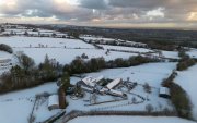 La imagen muestra un paisaje rural cubierto de nieve y edificios agrícolas en el Reino Unido durante una importante ola de frío a inicios de 2026.