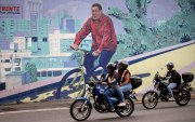 Motociclistas transitando frente a un mural del fallecido presidente de Venezuela, Hugo Chávez, este lunes 2 de febrero de 2026, en Caracas (Venezuela).
