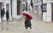 Una vecina de Grazalema (Cádiz) camina por una calle inundada debido a las intensas lluvias.