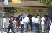 Un grupo de personas realizan fila en cajeros automáticos de una entidad bancaria en Quito.