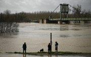 Personas en un sendero rodeado de una zona inundada en Marmande, suroeste de Francia, el 12 de febrero de 2026, mientras la tormenta Nils provoca inundaciones excepcionales a lo largo del río Garona.