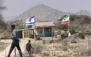 La gente camina junto a las banderas de Israel y Somalilandia que ondean juntas en la entrada de una granja de frutas.