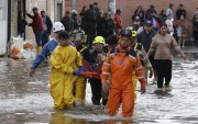 Integrantes de organismos de rescate socorren a un hombre en una calle inundada por fuertes lluvias este jueves, en Facatativá (Colombia).