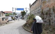 Un hombre carga un costal con productos agrícolas y lo atraviesa hasta cruzar el paso fronterizo.