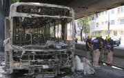 Bomberos observan los restos de un autobús incendiado por supuestos integrantes de una facción criminal, en respuesta a la muerte de Claudio Augusto dos Santos en Río de Janeiro