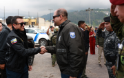 El presidente Daniel Noboa estrecha la mano del ministro del Interior, John Reimberg, durante un acto oficial acompañado por personal militar.