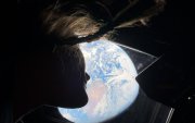 La astronauta de la NASA y especialista de la misión Artemis II, Christina Koch, mira por una de las ventanas de la cabina principal de la nave Orion, observando la Tierra mientras la tripulación viaja hacia la Luna.