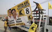 Personas sostienen una valla publicitaria del candidato a la Presidencia de Perú Carlos Álvarez y el diputado Julio Rojas este sábado, en Lima (Perú).