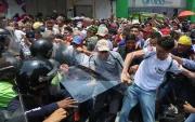 Personas exigen aumentos salariales mientras se enfrentan con integrantes de la policía en una manifestación este jueves, en Caracas (Venezuela).