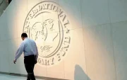Una persona camina a lado del logo del Fondo Monetario Internacional.