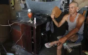 En el sur de Guayaquil, moradores del suburbio intentaron aliviar el calor con cualquier objeto ante la falta de energía eléctrica, que les impedía encender ventiladores.