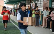 Integrante de la Oficina Nacional de Procesos Electorales (ONPE) carga una caja para empezar la instalación de una de las mesas de votación en un colegio de Lima.