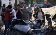 Familiares de las víctimas del atentado ocurrido en la Vía Panamericana lloran este domingo frente a los escombros de los vehículos destruidos en Cajibío (Colombia).