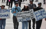 Personas sostienen carteles durante la masiva marcha por el Día Internacional del Trabajo, este viernes 1 de mayo de 2026, en Quito.