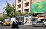Mujeres caminan junto a pancartas instaladas a lo largo de la carretera con imágenes del asesinado líder supremo de Irán, el ayatolá Ali Khamenei (izquierda), y del líder supremo, el ayatolá Mojtaba Khamenei, en Teherán.