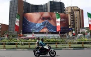 Personas circulan en motocicleta cerca de una valla publicitaria antiestadounidense con una foto de Donald Trump en la plaza Valiasr de Teherán, Irán, el 6 de mayo de 2026.