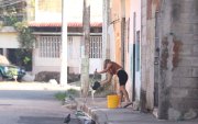 Una mujer limpió la vereda en el sector donde fue abandonado el cadáver de un hombre, frente a una escuela, en el Guasmo Sur de Guayaquil.