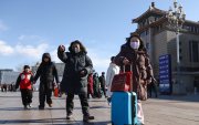 Personas caminan en las calles de Beijing, en China, al fondo un edificio.