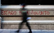 Un policía camina frente a un grafiti en La Paz, en medio de las protestas que marcan la primera crisis política del Gobierno de Rodrigo Paz.