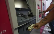 Personas usan los cajeros automáicos para retirar o depositar dinero.