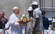 El papa León XIV recibe flores de dos voluntarios para protagonizar una ofrenda floral en el mar en recuerdo de los migrantes muertos.