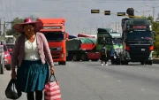 Una mujer quechua camina frente a vehículos de una caravana de transportistas para exigir el levante de los bloqueos de carreteras este lunes, en Cochabamba (Bolivia).