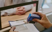 Referencial.Un funcionario estampa la aprobación en un trámite, mientras un solicitante espera la resolución en la oficina.