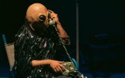 La obra transcurre en un espacio íntimo que remite a una sala. Desde allí, el intérprete comparte pensamientos, canciones y acciones performáticas