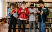 Estudiantes consultan sus teléfonos en una biblioteca, mientras Noruega restringe el uso de inteligencia artificial para menores de 6 a 13 años.