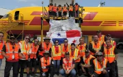 Personal de carga junto a un envío con la bandera de Panamá en un avión de DHL
