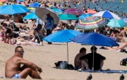 Turistas buscan sombra bajo sombrillas en playas europeas durante la ola de calor.
