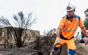 Personal de NGE Energie Solutions asegura las líneas eléctricas frente a viviendas dañadas por el fuego tras los incendios forestales en Le Porge, Francia.