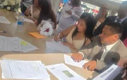 Una de las parejas firma el acta que oficializa su unión durante el matrimonio colectivo celebrado en Parque Samanes.