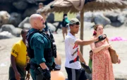 Un agente coordina con vecinos en la playa de Ceuta durante la llegada masiva de migrantes desde Marruecos.