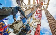 Dos personas hacen labor de mantenimiento en una torre donde se extrae petróleo.