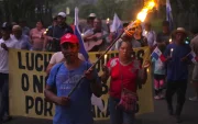Campesinos sostienen banderas y velas en una vigilia en rechazo al decreto ejecutivo que ordena la clausura de los cementerios comunitarios.