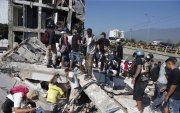 Personas caminan sobre los escombros de un edificio colapsado este lunes, en Cali (Colombia). Al menos 20 edificios sufrieron graves daños por consecuencia del terremoto de magnitud 7,4 que sacudió la mayor parte del país, con epicentro en la zona del Pacífico.